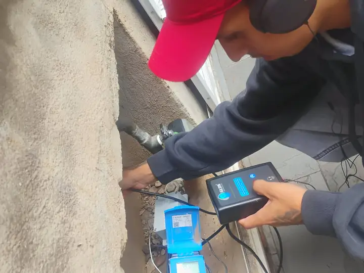 Técnico com geofone ao lado do hidrômetro no muro de uma casa